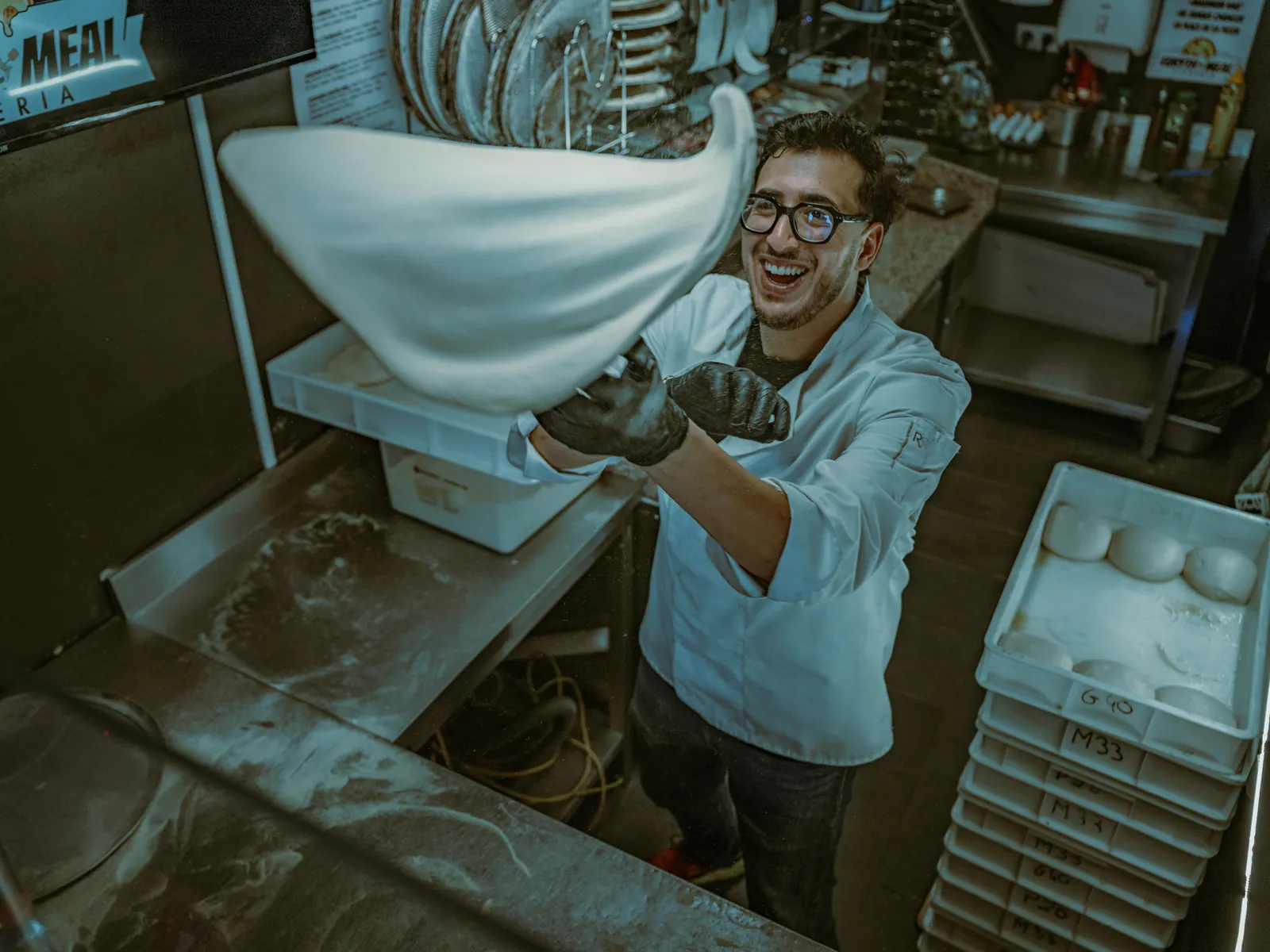 Pizzaiolo Euryth'meal étirant la pâte fraîche en cuisine