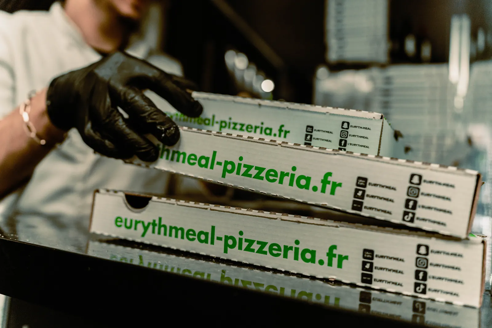 Boîtes à pizza Euryth'meal brandées eurythmeal-pizzeria.fr empilées en cuisine