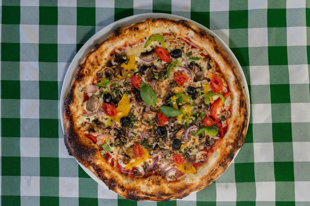Pizza aux légumes frais sur nappe vichy verte